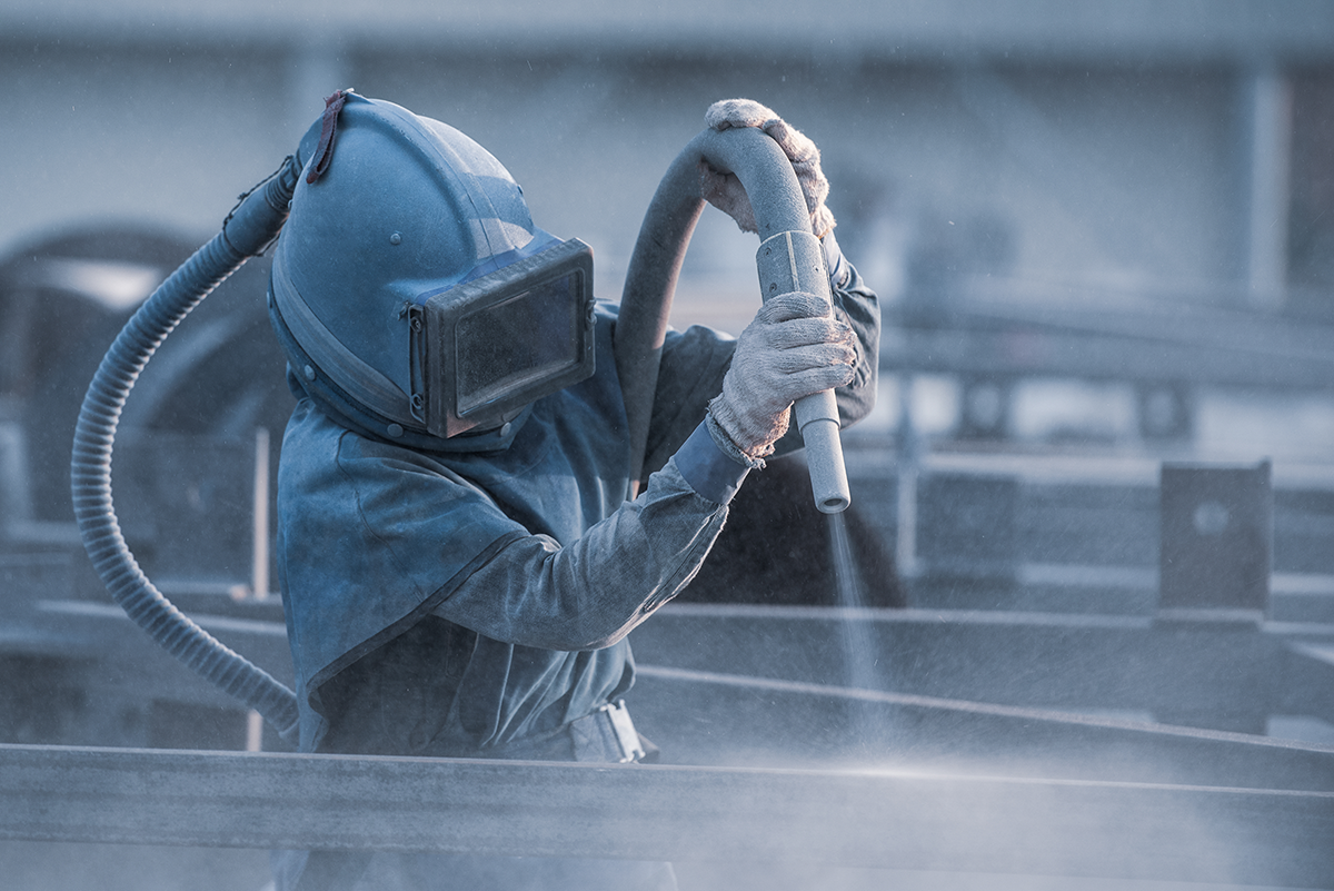 A person in PPE performing dustless blasting
